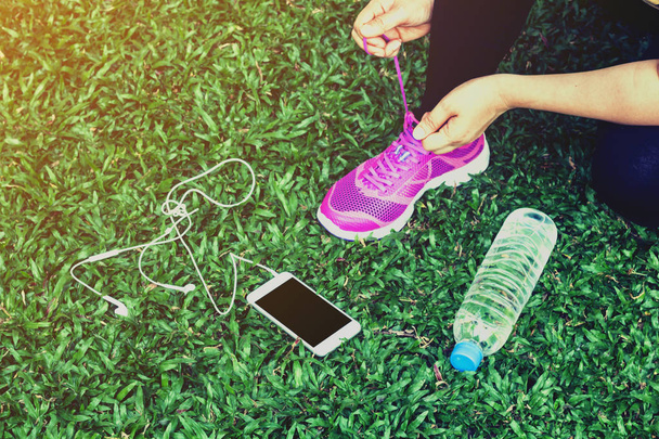 Läuferin mit Smartphone und Wasserflasche im Gras - Foto, Bild