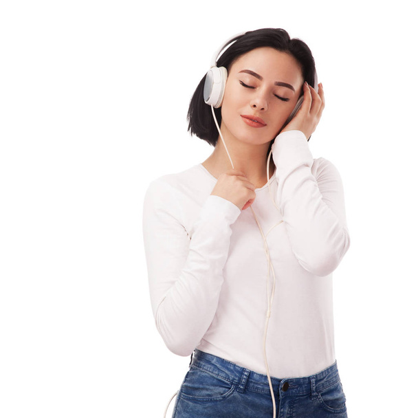 Young beautiful serene woman in headphones against white background - Fotó, kép