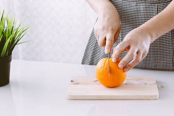Girl cutting orange with the knife - Photo, Image