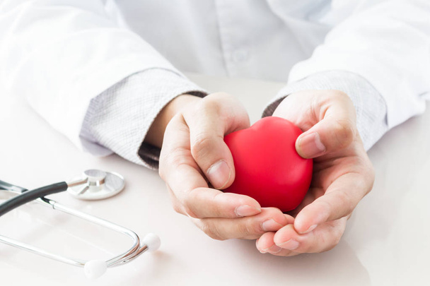 Médico masculino com estetoscópio segurando coração vermelho
 - Foto, Imagem