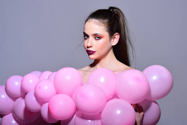 Retro girl with stylish makeup and hair. Fashion woman with many pink air balloons. Birthday decor and celebration. Balloon party on grey studio background. girl dreaming in punchy pastels trend - Foto, Imagen