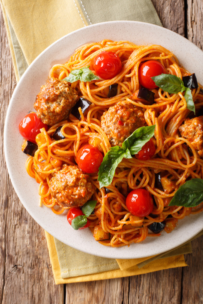 Spaghetti with meat balls, vegetables in a tomato sauce close-up on a plate on a table. Vertical top view from above, rustic styl - Photo, Image
