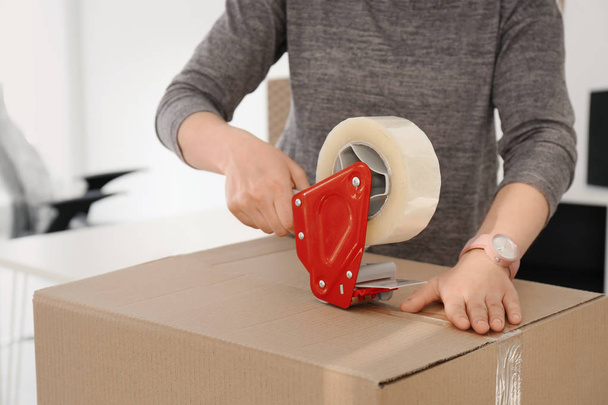 Young woman packing moving box indoors, closeup - Foto, imagen