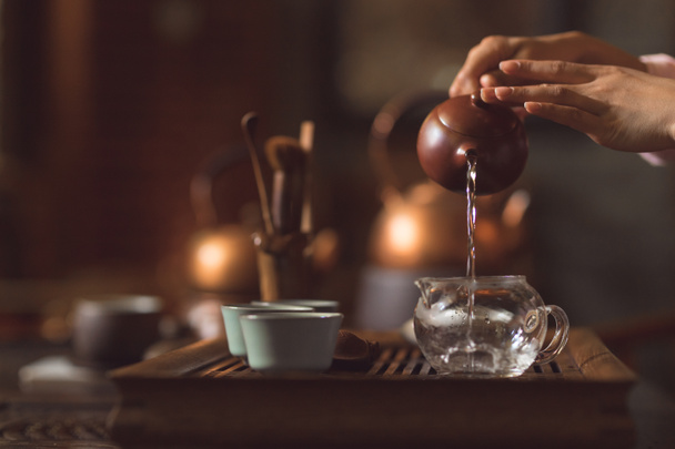 Mãos femininas derramando chá de um bule de chá closeup
 - Foto, Imagem