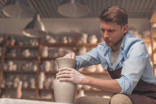 Young man at a potter's wheel in workshop - Photo, Image