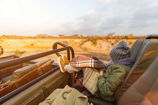 Adorable little girl in South Africa safari on cold morning game drive in open vehicle - 写真・画像