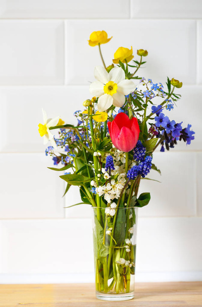 spring bouquet of wild flowers in a glass on a white background. House interior - Valokuva, kuva