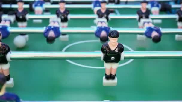 Tischfußball, Ballspiel zwischen Blau und Schwarz auf einem grünen Fußballfeld, Nahaufnahme der Figuren der Spieler - Filmmaterial, Video