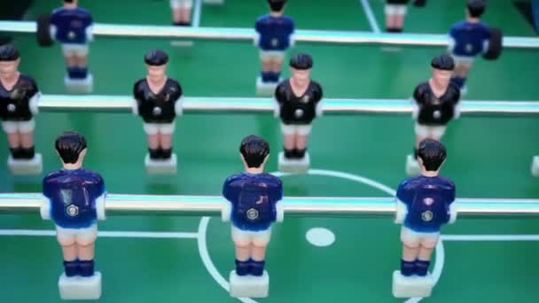 Tischfußball, Ballspiel zwischen Blau und Schwarz auf einem grünen Fußballfeld, Nahaufnahme der Figuren der Spieler - Filmmaterial, Video