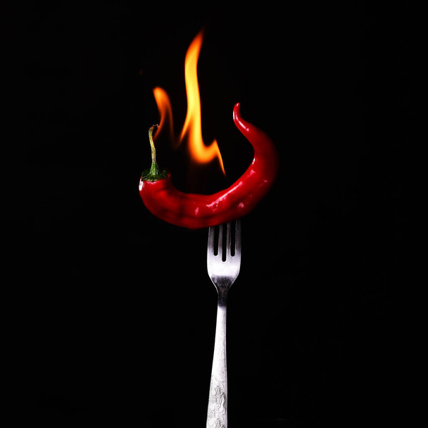 Widelec wbij do red hot chili na czarnym tle.  - Zdjęcie, obraz