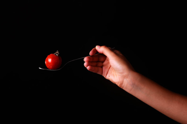 koken en voedsel concept - vrouwelijke hand met vork en tomaat - Foto, afbeelding