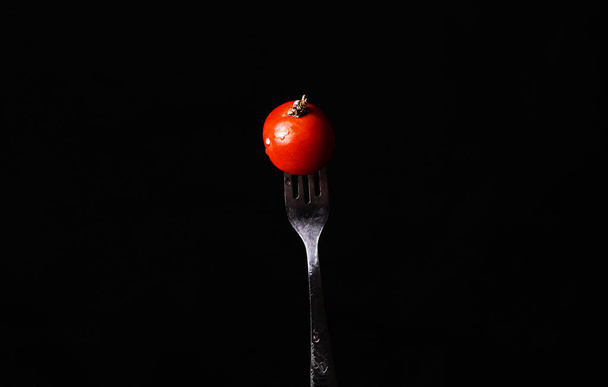 conceito de cozinha e comida - mão feminina com garfo e tomate
 - Foto, Imagem