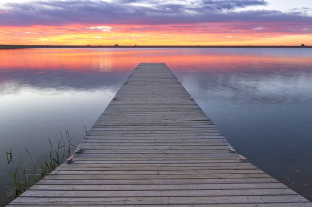amanecer o atardecer sobre un muelle de pesca o muelle de pesca con nubes de colores que se reflejan en el lago ubicado en el condado de Larimer, Colorado
 - Foto, Imagen