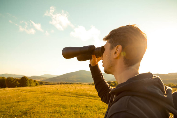 Hombre joven uso del binocular en el bosque. Camping turístico
 - Foto, Imagen