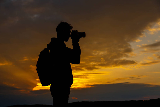silueta fotografa fotografujícího krajinu při západu slunce - Fotografie, Obrázek