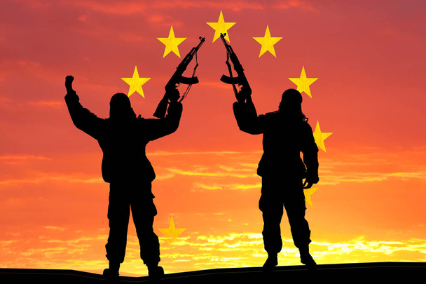 Silhouet van militaire soldaat, schot, bedrijf pistool, kleurrijke hemel, Concept van een terrorist. Silhouet terroristen met geweer, nationale vlag op de achtergrond - Europese Unie - Eu - Foto, afbeelding