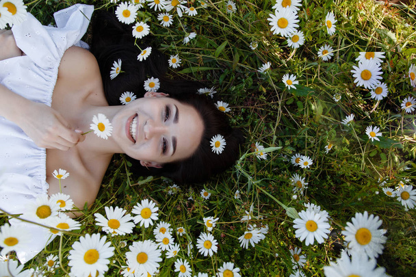 schöne Frau auf einer Blumenwiese, die ihre Zeit im Freien genießt. hübsche Mädchen entspannen im Freien, Spaß haben, Pflanze halten, glückliche junge Frau und Frühling grüne Natur, Harmoniekonzept - Foto, Bild
