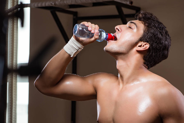 Thirsty man drinking water in sports gym - Photo, Image