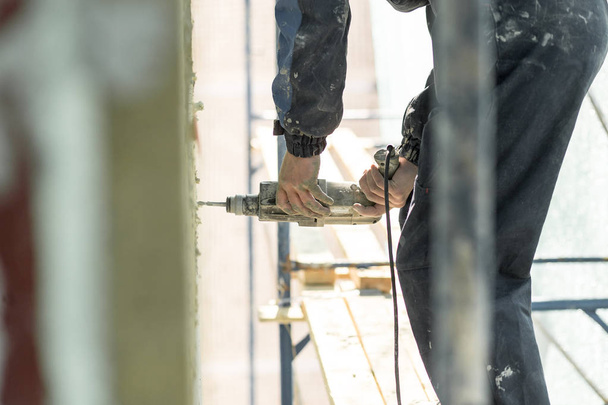 Hand drilling on the scaffolding on altitude. Concept repairing the wall panel - Fotoğraf, Görsel