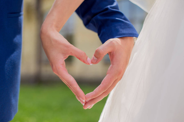 the bride and groom hold hands in the shape of a heart - Fotó, kép
