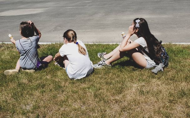 Three young girls sitting in grass, rear view - Photo, Image