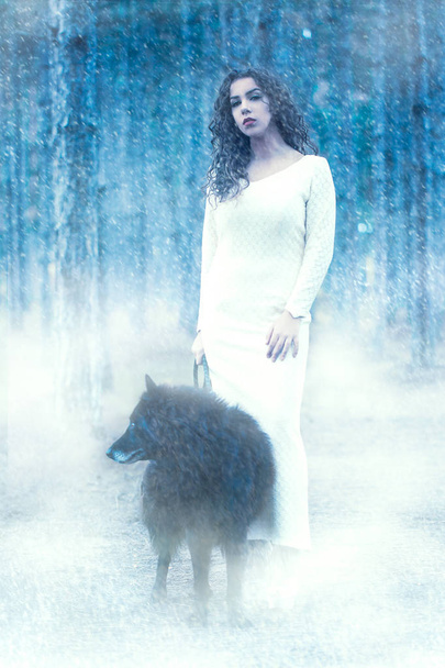 close-up photo of young curly brunette woman in white dress outdoor with black dog - Valokuva, kuva