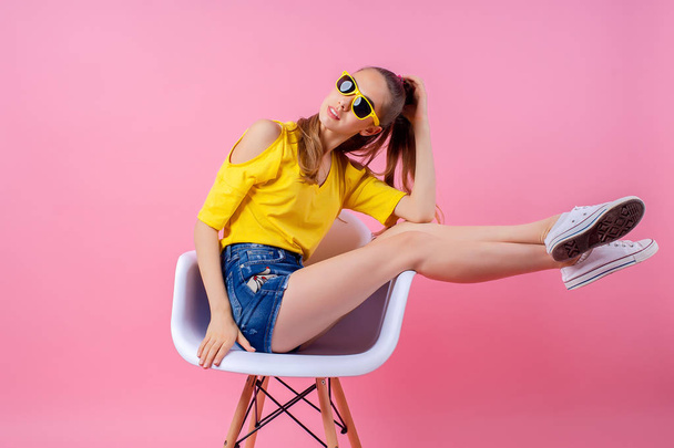 Playful teenage girl sitting in chair with legs raised - Valokuva, kuva