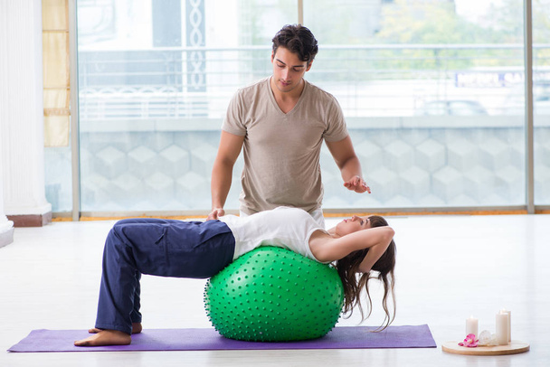 Entrenador personal ayudando a la mujer en el gimnasio con bola de estabilidad - Foto, Imagen