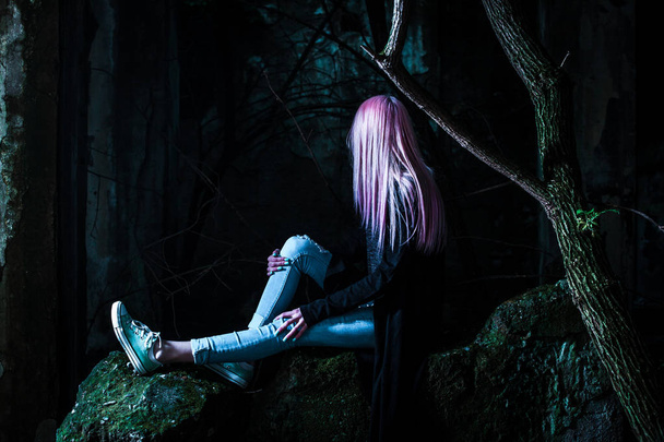 photo of young charming woman with pink hair and piercing sitting on stone - Photo, image