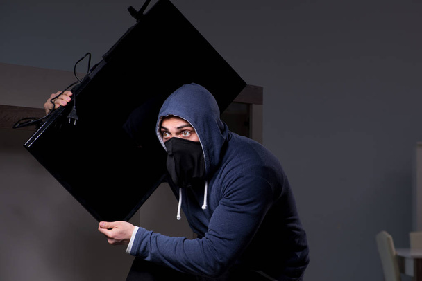 Burglar thief stealing tv from apartment house - Foto, afbeelding