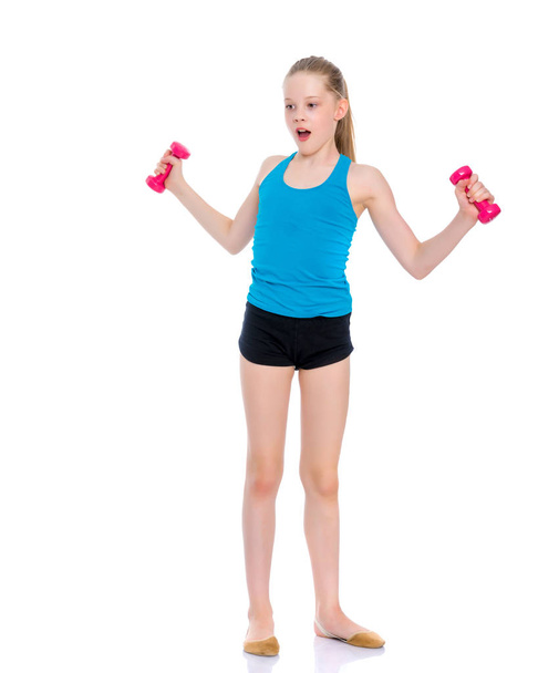 Little girl doing exercises with dumbbells. - Foto, afbeelding