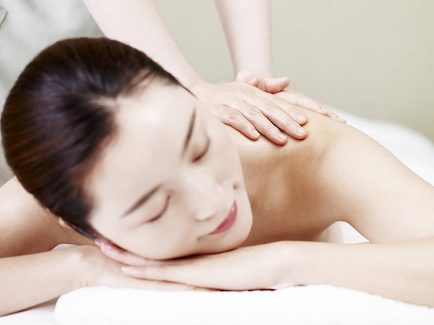 bela jovem asiático mulher deitado na frente na cama receber óleo massagem no spa salão, foco no massagista 's mãos
. - Foto, Imagem