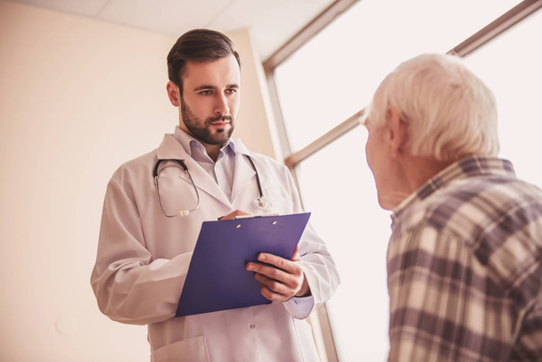 Un beau docteur parle avec un vieil homme et prend des notes pendant qu'il est à l'hôpital.
 - Photo, image