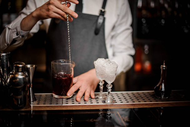 Bartender stirring a fresh and sweet summer alcoholic cocktail in glass on the bar counter - Fotoğraf, Görsel