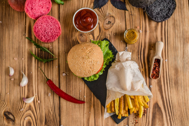 Tasty hamburger with meat and vegetables against a dark background. Fast food. It can be used as a background - Fotoğraf, Görsel
