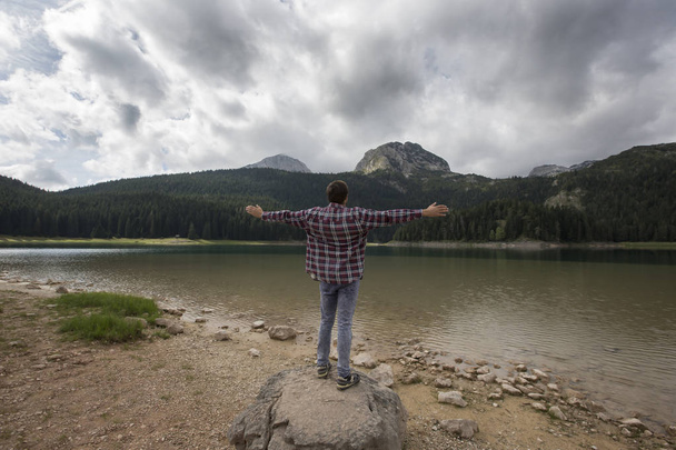 Jeune homme regardant Black Lake, Parc national Durmitor, Zabljak, Monténégro. Voyageur hipster profitant de la vue sur Black Lake
 - Photo, image