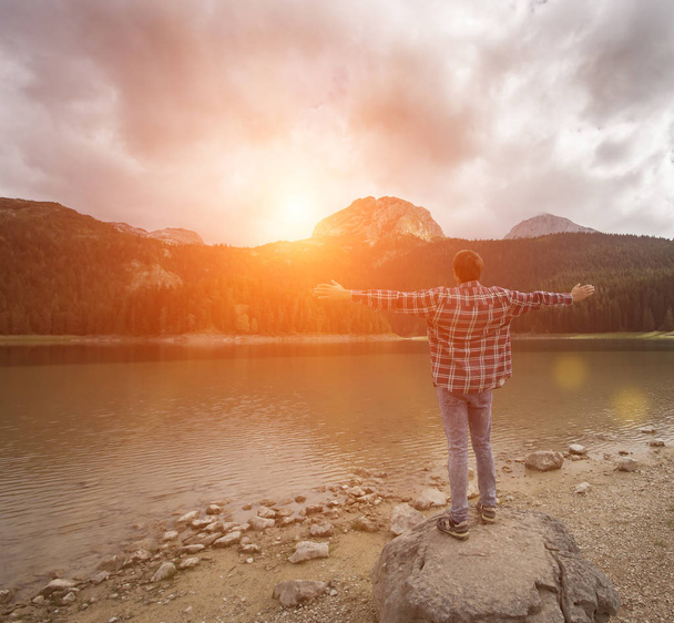 ブラックレイク、デュルモーター国立公園、ザブルジャック、モンテネグロを見ている若い男。黒湖の景色を楽しむヒップスター旅行者 - 写真・画像