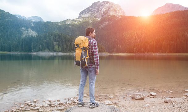ブラックレイク、デュルモーター国立公園、ザブルジャック、モンテネグロを見ている若い男。黒湖の景色を楽しむヒップスター旅行者 - 写真・画像