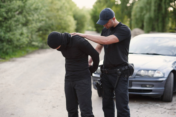 A police officer arrested an offender with the stolen car and handcuffed him close up. - Foto, Bild