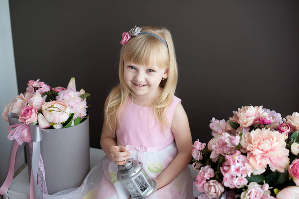 Küçük sarışın kız odasında çiçeklerle süslenmiş. Bir prenses pembe iç portresi. - Fotoğraf, Görsel