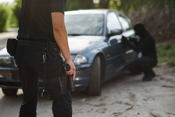 Полицейский с пистолетом в руке арестовал преступника, который угнал машину. Закон и справедливость
. - Фото, изображение