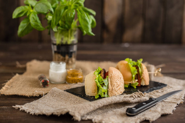 Leckere Hamburger mit Fleisch und Gemüse vor dunklem Hintergrund. Fast Food. es kann als Hintergrund verwendet werden - Foto, Bild