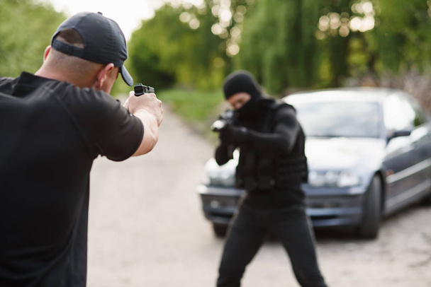 Shootout between a police officer and a offender. Stop Terrorism and Crime. The police officer and the terrorist are aiming each other. - Photo, Image