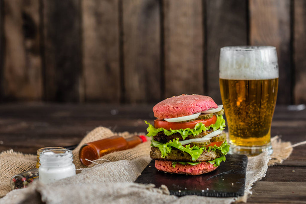 Tasty hamburger with meat and vegetables against a dark background. Fast food. It can be used as a background - Zdjęcie, obraz