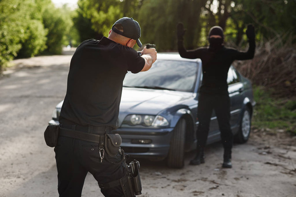 The policeman is targeting an offender near the stolen car. Stop criminality. - Fotó, kép