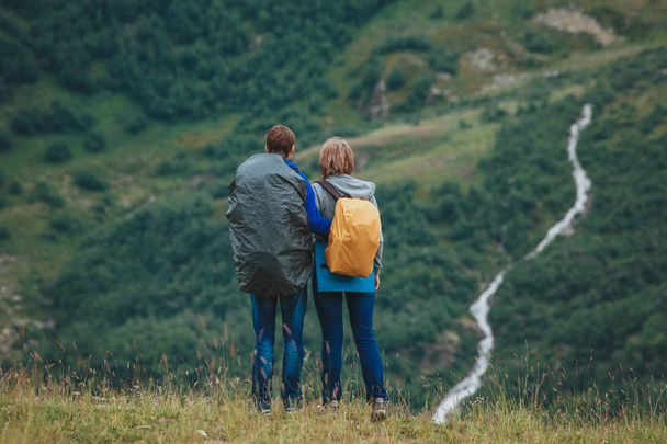 Man and woman standing and hugging on the top of the mountain, autumn hike with backpacks, alpine view - Foto, Imagen