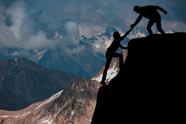 Mannelijke en vrouwelijke wandelaars beklimmen bergklif en een van hen geven helpende hand. Mensen helpen en, team werk concept. - Foto, afbeelding