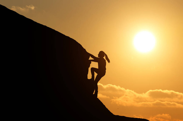 meisje silhouet op de top van een berg klimmen - Foto, afbeelding