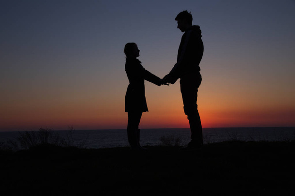 silhouette gars et fille sur un beau coucher de soleil tenant la main
 - Photo, image