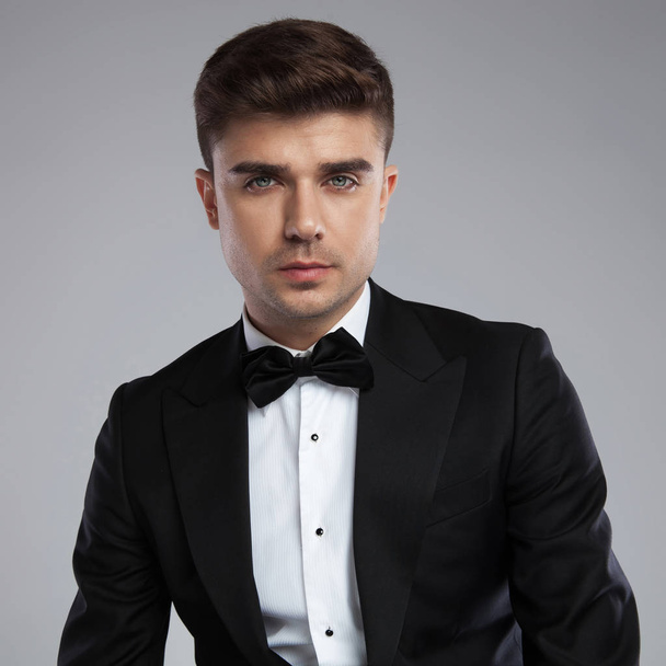 retrato de joven empresario en traje negro y corbata negra sobre fondo gris claro
 - Foto, Imagen